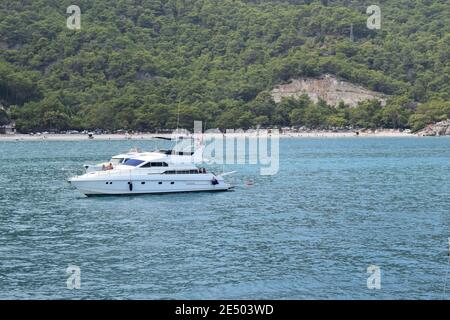 Private Yacht im Mittelmeer auf dem Hintergrund der Berge. Ein luxuriöses Motorboot, das durch das wunderschöne blaue Wasser fährt. Seitenansicht. Antaly Stockfoto