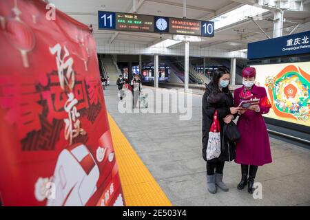 Chongqing, China. Januar 2021. Ein Mitarbeiter verteilt Flugblätter zur Verhütung von Epidemien an einen Passagier am Bahnhof Chongqingbei in Chongqing, Südwestchina, 25. Januar 2021. Die Präventions- und Kontrollbemühungen gegen die COVID-19-Epidemie werden an Bahnhöfen in Chongqing verstärkt, um die Sicherheit der Passagiere zu schützen. Quelle: Huang Wei/Xinhua/Alamy Live News Stockfoto