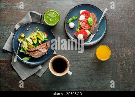 Frühstück mit Getränken und vegetarischen Sandwiches mit Avocado, Tomaten, Kräutern und Käse. Kontinentales leckeres gesundes Frühstück Stockfoto