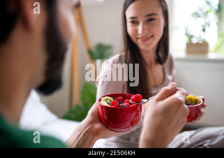 Junges Paar in der Liebe essen Frühstück auf dem Bett drinnen zu Hause. Stockfoto
