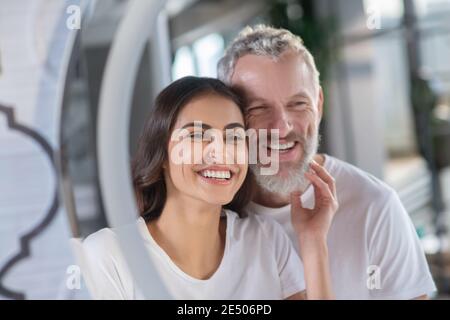 Lächelnder Mann und Frau, die auf den Spiegel schauen Stockfoto