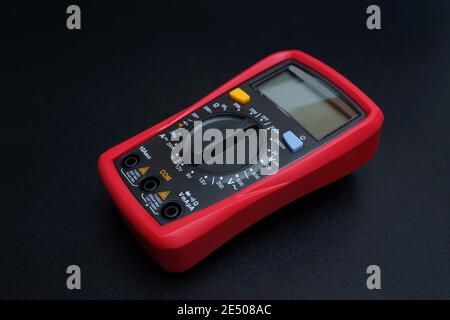 Rotes Digitalmultimeter auf schwarzem Hintergrund - Multimeter ist ein elektronisches Messgerät für Spannung, ampere, Widerstand Stockfoto