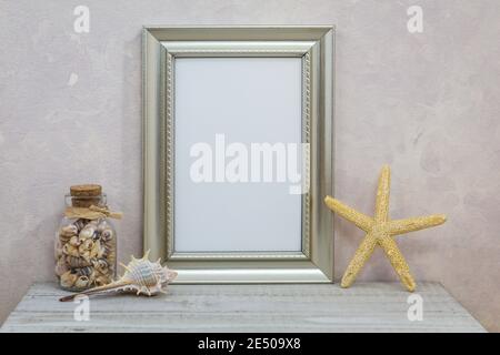 Silver Frame Mockup mit Muscheln gegen rosa strukturierte Wand für Frühling, Sommer, Meer, Küste, Strand, Urlaub, Urlaub, Party-Thema. Stockfoto