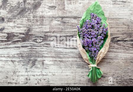 Lavendelstrauß in Papierverpackung mit Platz für Text. Frischer Lavendel Blumen Gruß Bouquet auf alten rustikalen Holztisch. Flatlay französisch Stockfoto