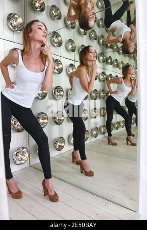 High Heel Frau posiert gegen Bühnenbeleuchtung mit surrealen Reflexionen Stockfoto