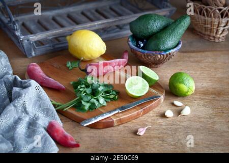 Kochen mexikanische Guacamole - Avocado, Limette, Zitrone, Pfeffer, Knoblauch und Koriander auf einer hölzernen Tisch. essen Hintergrund mit Kopie Raum Stockfoto