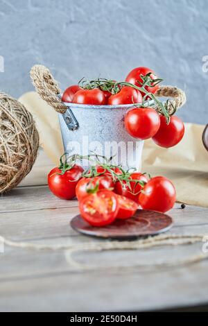 Eimer mit Tomaten und halbgeschnittenen Tomaten auf Holztisch Stockfoto