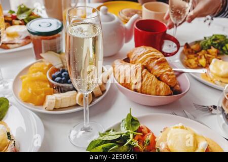 Ein Glas Champagner aus der Nähe auf dem Tisch mit verschiedenen Frühstück Und Brunch-Gerichte Stockfoto