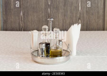 Set mit Gewürzen und Gewürzen in einem Metallständer. Diese befindet sich auf einer weißen Tischdecke. Nahaufnahme. Stockfoto