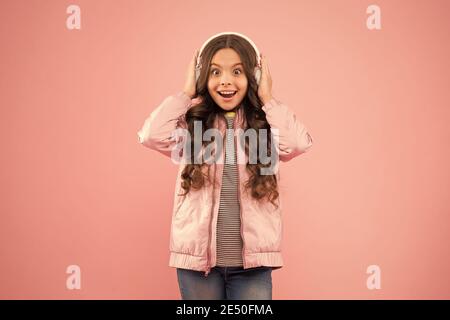 Das klingt großartig. Schallschwingungen. Musik und Technologie. Audio-Sound. Spaß und Unterhaltung. Musik ein. Glückliches Kind genießen Sie hören Soundtrack. Kleines Mädchen tragen Kopfhörer rosa Hintergrund. Stockfoto