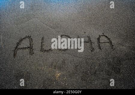 Wort Aloha schrieb an einem schwarzen Sandstrand, Big Island Hawaii Stockfoto