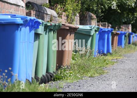 Lange Reihe verschiedenfarbiger Mülltonnen auf der Hinterseite des Hauses in Troon, South Ayrshire, Schottland. Stockfoto