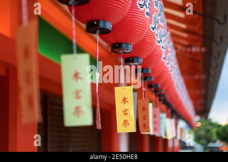 Nahaufnahme einer Reihe von roten Windlicht Laterne mit Farbige Kanji Schriften baumeln in einem japanischen Tempel Stockfoto