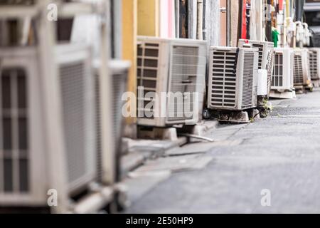 Nahaufnahme einer Reihe von externen Klimaanlagen, die in einer Seitengasse gesäumt sind Stockfoto