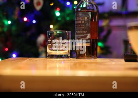 Whisky-Glas mit drei Maßnahmen markiert auf einer Flasche talisker Storm Single Malt Whisky, weihnachtsbaum Licht im Hintergrund Stockfoto