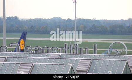 MÜNCHEN, DEUTSCHLAND - 11. OKTOBER 2015: Blick auf das MUC-Terminalgebäude des Münchner Flughafens mit einem Flugzeug im Hintergrund Stockfoto
