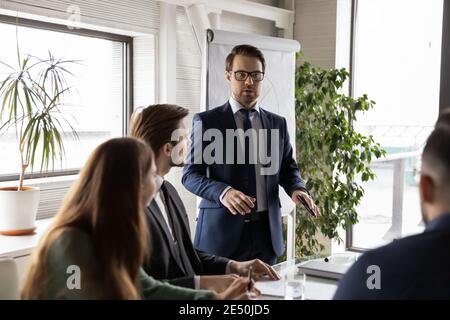 Selbstbewusster Geschäftsmann, der eine Brille trägt und Flipchart im Sitzungssaal präsentiert Stockfoto