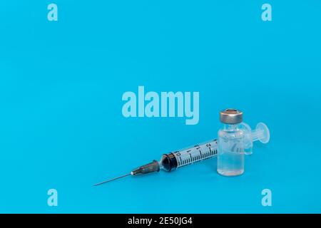 Medizin infektiöses Konzept. Impfstoff und Spritzeninjektion auf blauem Hintergrund. Seine Verwendung für Prävention, Immunisierung und Behandlung. Stockfoto