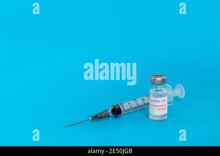 Spritzeninjektion und Coronavirus-Impfstoff COVID-19 auf blauem Hintergrund. Coronavirus-Impfstoff Medizin infektiöses Konzept. Stockfoto