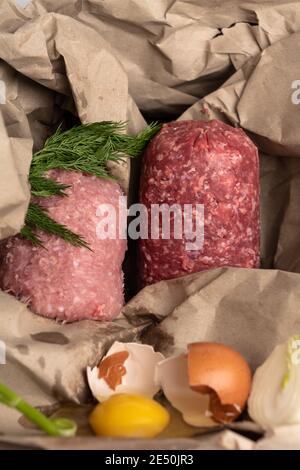 Rohzutaten für Koteletts, Fleischpasteten oder Bälle, Bio-Hackfleisch gemischt, Ei, Zwiebel, Kräuter, Dill auf Papier Öko Hintergrund Stockfoto