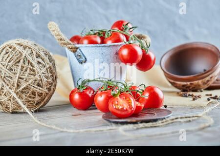 Eimer mit Tomaten und halbgeschnittenen Tomaten auf Holztisch Stockfoto