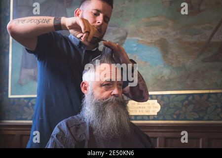 Edinburgh, Schottland - September 30 2017: Ein angesagter älterer Mann mit einem Hipster-Bart bekommt einen Haarschnitt in einem Pop-up-Friseurladen im Scottish National Stockfoto