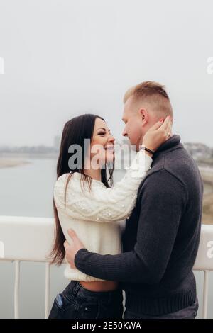 Die junge Frau umarmt ihren Mann sanft vor dem Hintergrund einer nebligen Flusslandschaft. Hochwertige Fotos Stockfoto