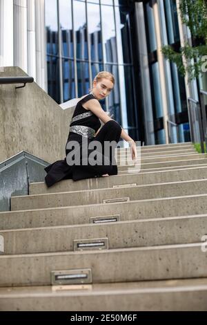 Europäische Frau in schwarzen Kleidern sitzt auf Betontreppen Stockfoto