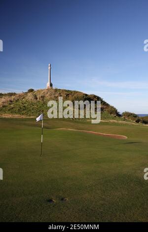 Turnberry, Ayrshire, Schottland, Großbritannien. Turnberry war Memorial EIN doppeltes keltisches Kreuz errichtet von den Menschen der Kirkoswald Parish in 1923 zu Ehren der Flieger stationiert Turnberry Air Field, die während des Ersten Weltkriegs starb. Im November 1990 wurden vier Abschnitte an die Basis des Denkmals mit den Namen derer, die in Turnberry während des Zweiten Weltkriegs gestorben sind, hinzugefügt. Blick vom 12. Grün auf die Gedenkstätte Stockfoto