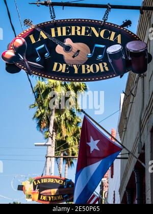 Ybor City, FL - 16. März 2017: Zeichen für die beliebte La Herencia De Ybor Zigarrenladen, Lounge und Bar, mit der kubanischen Flagge fliegen unten. Stockfoto