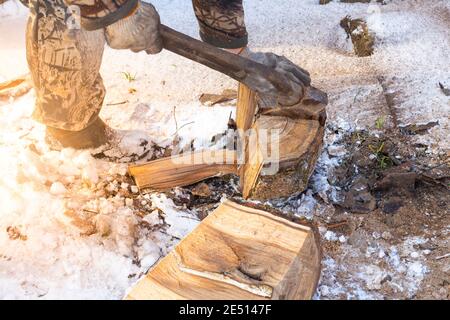 Ein Mann hackt Holz mit einer Axt auf dem Land. Brennstoff für den Kessel. Überflutung des Hauses. Stockfoto