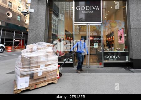 New York, USA. Januar 2021. Ein Mann zieht eine Palette von Vorräten, die an das Godiva Chocolate-Geschäft in NYC geliefert werden, da Godiva Chocolatier bekannt gab, dass es aufgrund der wirtschaftlichen Auswirkungen der COVID-19-Pandemie alle 128 Einzelhandelsgeschäfte in Nordamerika schließen werde, New York, NY, 25. Januar 2021. Gegründet 1926 in Belgien und im Besitz des türkischen Konglomerats Yildiz Holding sagte, dass alle stationären Geschäfte, einschließlich Cafés und Boutiquen in den Vereinigten Staaten und Puerto Rico bis zum kommenden Frühjahr. (Foto von Anthony Behar/Sipa USA) Quelle: SIPA USA/Alamy Live News Stockfoto