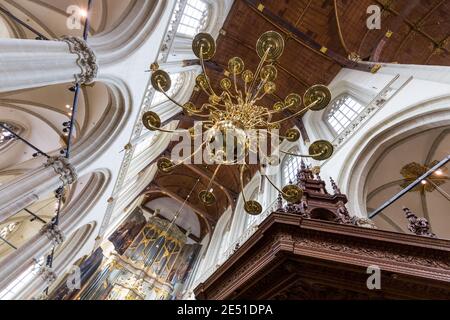 Weitwinkelansicht von unten auf das Gewölbe einer niederländischen Kathedrale, mit einem goldenen Kronleuchter und einer Reihe von spitzen Bögen Stockfoto