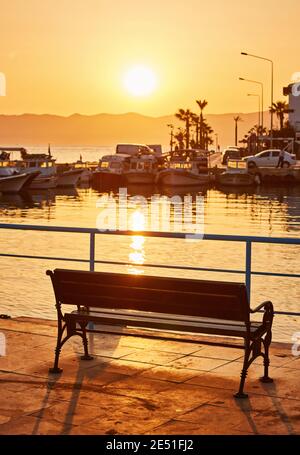 Einsame Bank auf der Promenade am Meer bei Sonnenuntergang Stockfoto