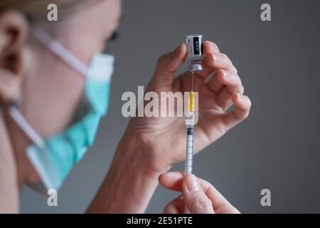Original Pfizer BioNTech COVID-19 Impfstofffläschchen von Mädchen in einer Maske in der Hand halten. Echtes Impffoto. Selektiver Fokus. Stafford, Vereinigtes Königreich - Januar Stockfoto