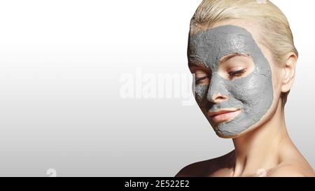 Schöne Frau, Die Weiße Gesichtsmaske Anwendet. Schönheitsbehandlungen. Close-up Portrait of Spa Girl Tragen Sie Clay Gesichtsmaske auf grauem Hintergrund. Stockfoto