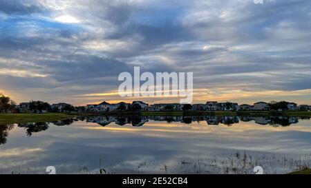 Wunderschöne rosa, orange und blau Sonnenuntergang spiegelt sich auf einem See in einem Vorort. Stockfoto