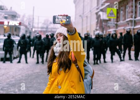 Nischni Nowgorod, Russland - Januar 23 2021: Das Mädchen lächelt und macht ein Selfie vor dem Hintergrund der Polizei Stockfoto