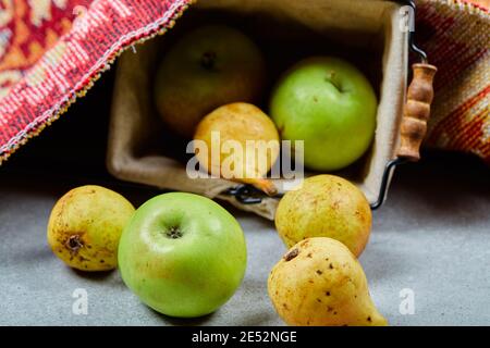 Reife Äpfel und Birnen im Korb und auf blauem Hintergrund Stockfoto