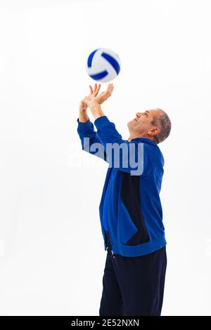 Ein alter Mann in einem blauen Trainingsanzug spielt Ball auf einem weißen isolierten Hintergrund. Hochwertige Fotos Stockfoto