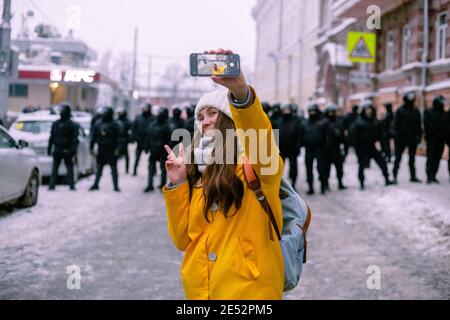 Nischni Nowgorod, Russland - Januar 23 2021: Das Mädchen lächelt und macht ein Selfie vor dem Hintergrund der Polizei. Stockfoto