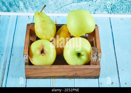 Frische Äpfel und Birnen in einer Holzkiste auf Blau Hintergrund Stockfoto