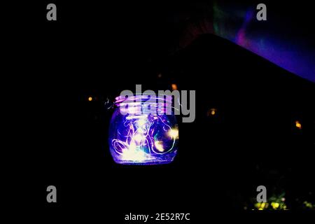 Und hält ein Glasglas mit LED-Leuchten gefüllt Stockfoto