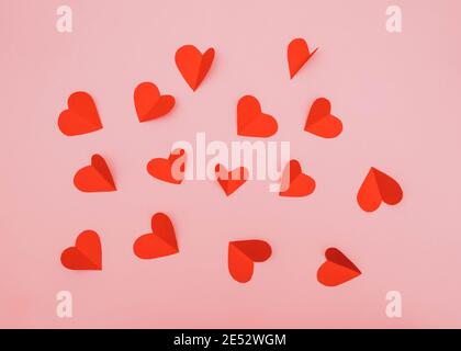 Kleine rote Papierherzen auf rosa Hintergrund romantische Symbole Stockfoto