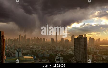Stadtbild mit Wolkenkratzergebäude. Morgensonne durch den Himmel mit grauen Wolken. Stadt am Fluss mit goldenem Sonnenaufgang. Urbanes modernes Gebäude. Stockfoto
