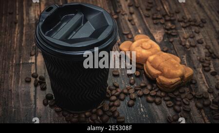 Ein Glas Kaffee und Gebäck, Gebäck mit Teddybär, aromatischer Kaffee mit Keksen, geröstete Kaffeebohnen. Frühstück am Morgen. Stockfoto