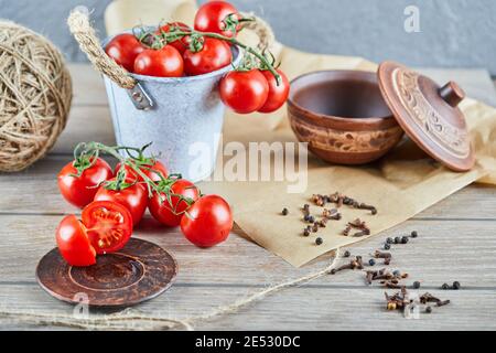 Eimer mit Tomaten und halbgeschnittenen Tomaten auf Holztisch Stockfoto