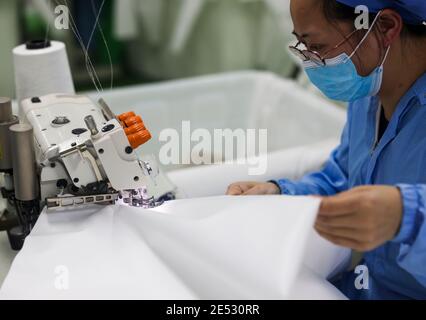 Chongqing, China. Januar 2021. Ein Arbeiter stellt in einer Werkstatt im Landkreis Fengdu in Chongqing, Südwestchina, Schutzanzüge an, 25. Januar 2021. Die Fabrik produziert rund um die Uhr Schutzanzüge, um die Binnennachfrage zu befriedigen, während das Land gegen den jüngsten Ausbruch der COVID-19-Fälle kämpft. Quelle: Liu Chan/Xinhua/Alamy Live News Stockfoto