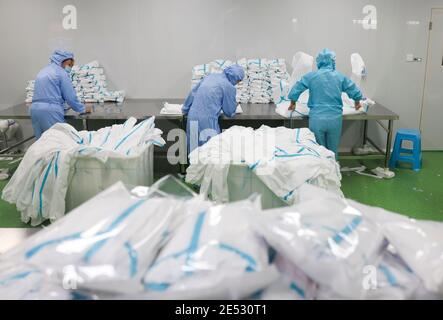 Chongqing, China. Januar 2021. Arbeiter packen Schutzanzüge in einer Werkstatt im Landkreis Fengdu in Chongqing, Südwestchina, 25. Januar 2021. Die Fabrik produziert rund um die Uhr Schutzanzüge, um die Binnennachfrage zu befriedigen, während das Land gegen den jüngsten Ausbruch der COVID-19-Fälle kämpft. Quelle: Liu Chan/Xinhua/Alamy Live News Stockfoto