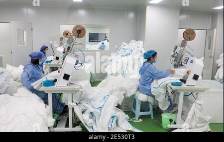 Chongqing, China. Januar 2021. Arbeiter stellen in einer Werkstatt im Landkreis Fengdu in Chongqing, Südwestchina, Schutzanzüge an, 25. Januar 2021. Die Fabrik produziert rund um die Uhr Schutzanzüge, um die Binnennachfrage zu befriedigen, während das Land gegen den jüngsten Ausbruch der COVID-19-Fälle kämpft. Quelle: Liu Chan/Xinhua/Alamy Live News Stockfoto